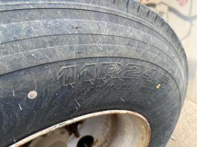 Trailer wheel with tire markings and rim; tread pattern visible with dirt and grime.