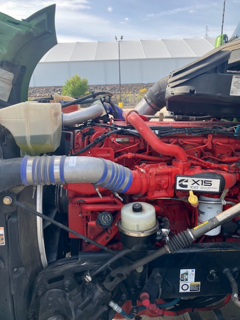 Kenworth T680 engine bay with red engine, blue hoses, coolant reservoir, and X15 badge visible.