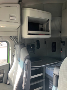 Truck interior cabin area with upper bunk shelf and a fold-out compartment; visible text includes no legible labels or numbers.