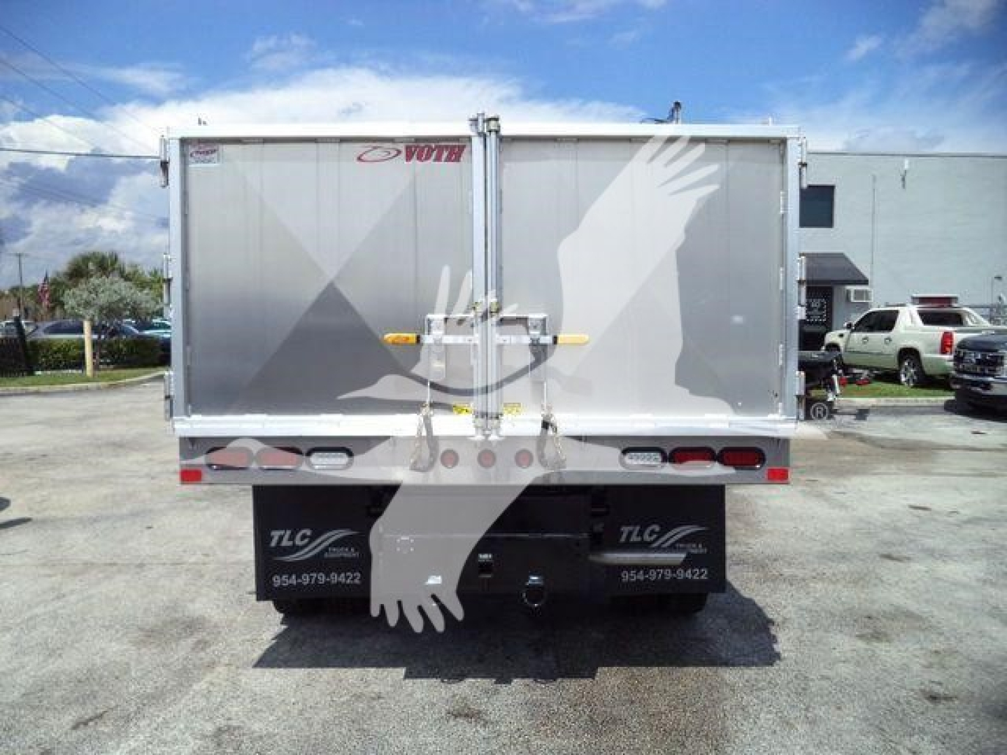 Back of a Ford F-550 dump truck bed showing TLC truck body with contact numbers and logos on the mud flaps.