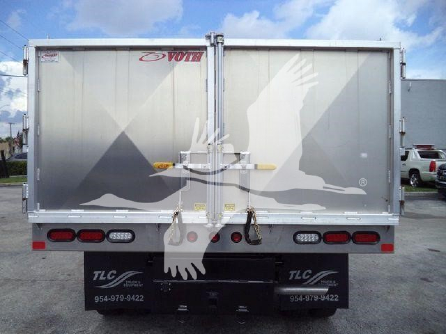 Back view of a Ford F-550 dump truck with dual rear doors and trailer hitch, featuring white graphic crane-like birds and rear lights.