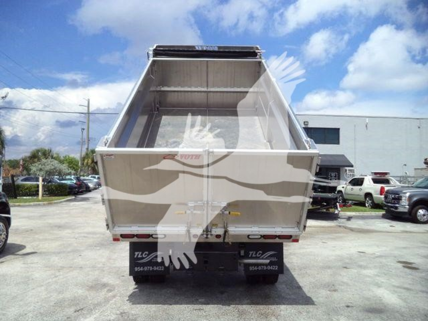 Back of a Ford F-550 dump bed trailer showing the rear with the bed raised. There are taillights, bumper, and a license plate area. The truck has TLC branding on mudflaps and decals.