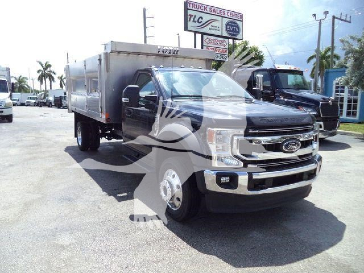 Ford F-550 dump body truck in a dealership lot showing front grille and cab with aluminum dump bed.