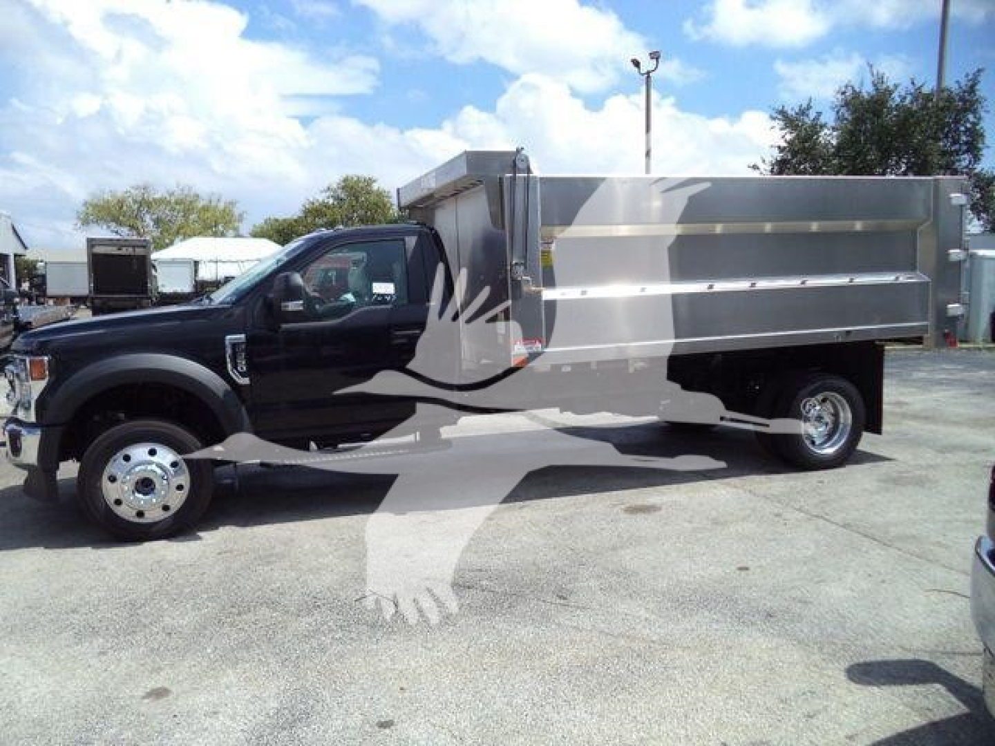 Ford F-550 dump truck chassis with aluminum dump bed, side view showing front wheels and cab.
