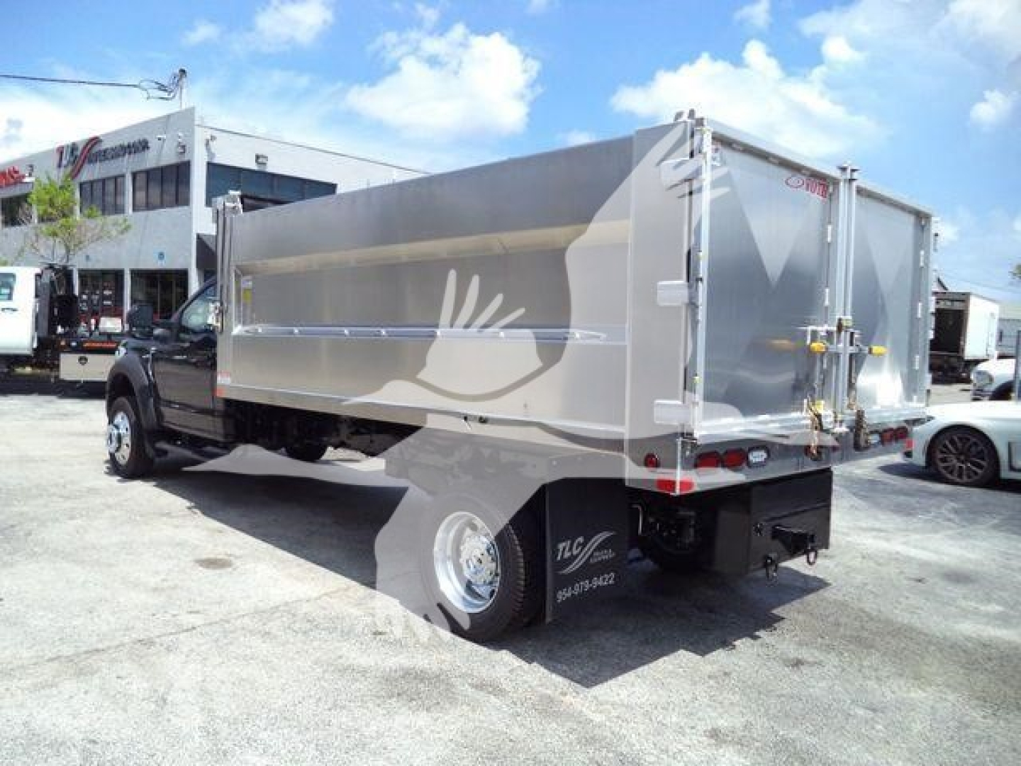 Ford F-550 dump truck with aluminum dump body, rear view showing side panel and hydraulic lid, in-service condition