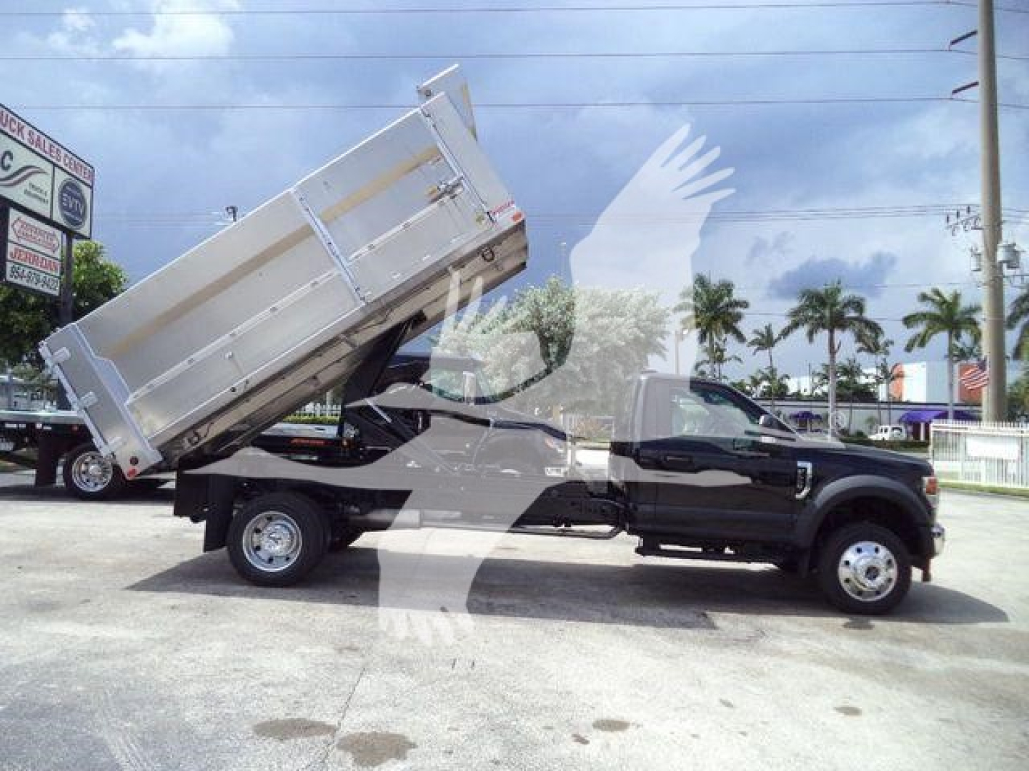 Ford F-550 dump truck in-service chassis with elevated bed and aluminum dump body, side profile view.