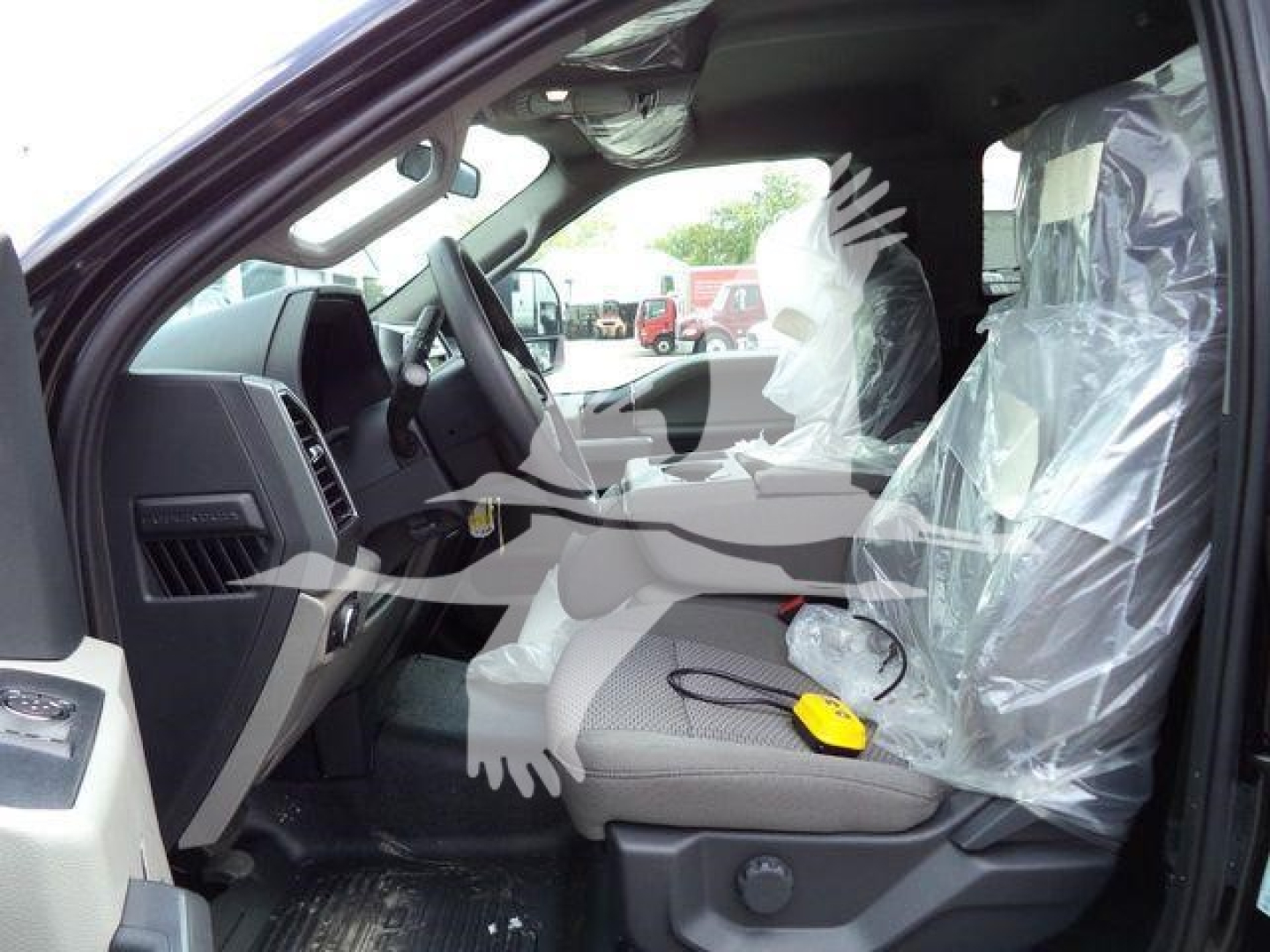 Ford F-550 interior driver seat area with plastic protective covers and wiring tester on seat.
