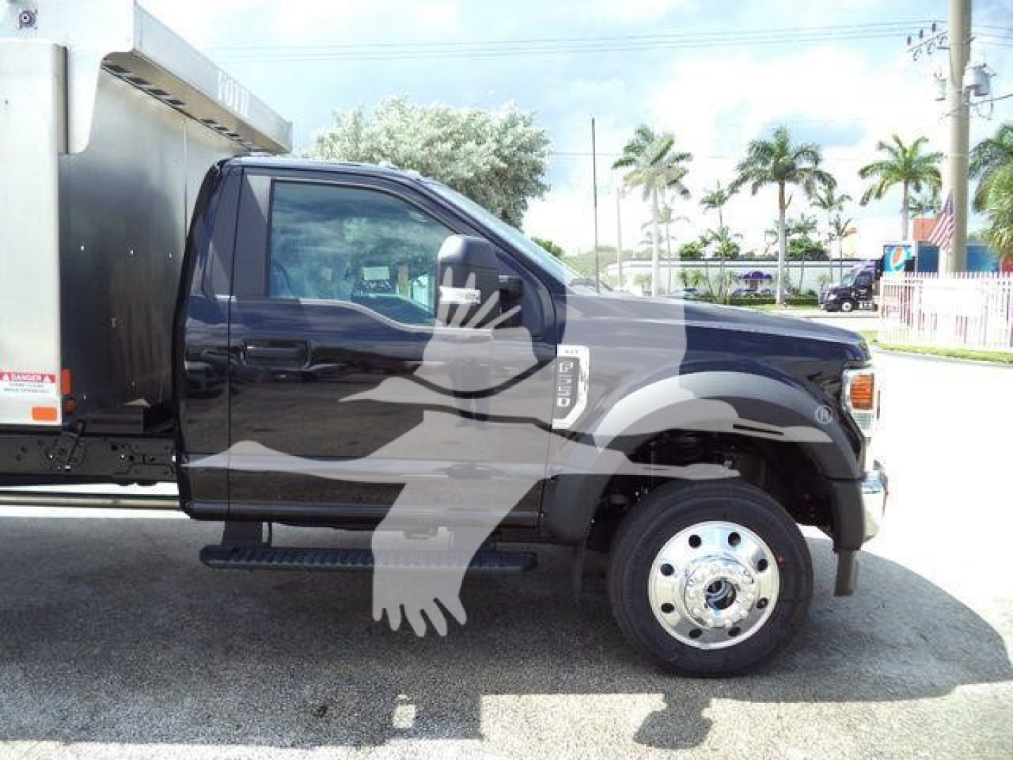 Ford F550 cab and chassis side view showing front wheel and steps with stock number F5504X4ALUMDMP on truck.