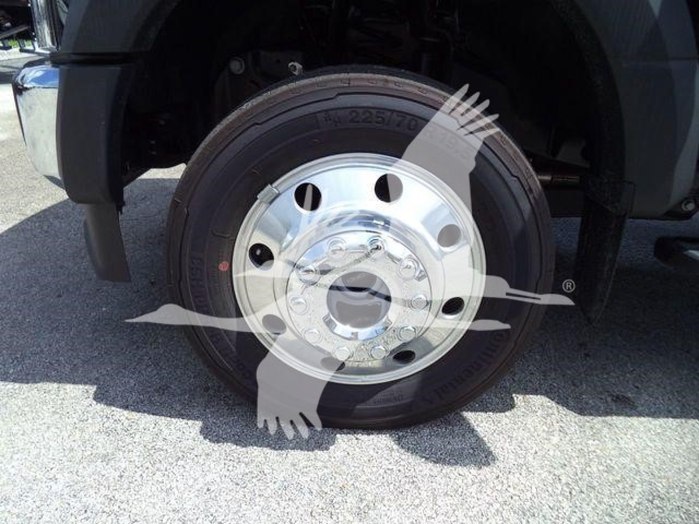 Truck wheel close-up showing polished steel hub and tire on Ford F-550 front wheel well.