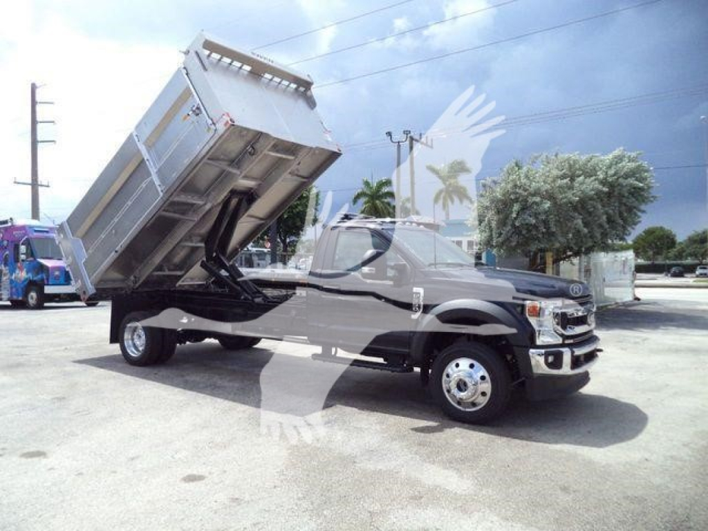 Ford F-550 diesel dump truck with bed raised in a dealership lot showing front cab and lifted cargo bed.
