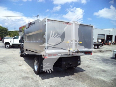 Ford F-550 dump truck body rear view showing aluminum dump bed with taillights and hinged tailgate, off-road lot background.