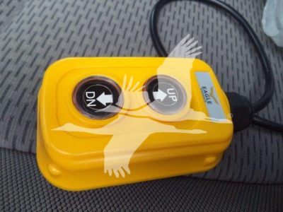Yellow portable air compressor with two circular controls labeled DN and UP, connected by a black power cord, sitting on a vehicle seat.