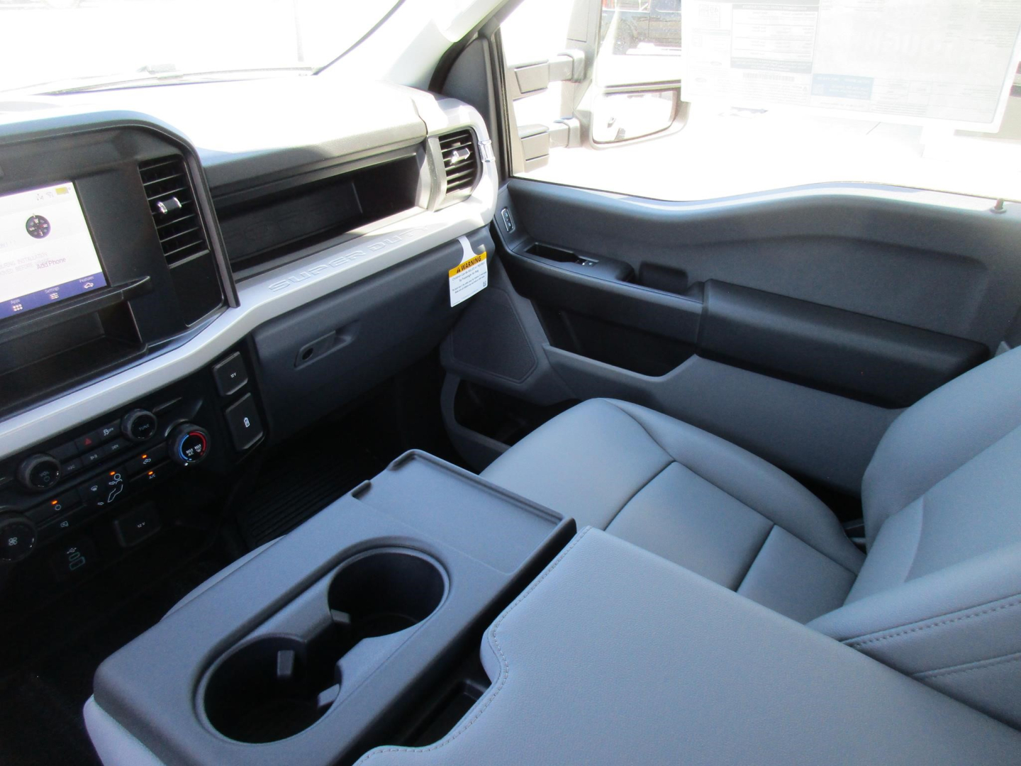 Interior of a Ford F-250 cabin showing dashboard with touchscreen display, center console with cup holders, and front passenger seat.