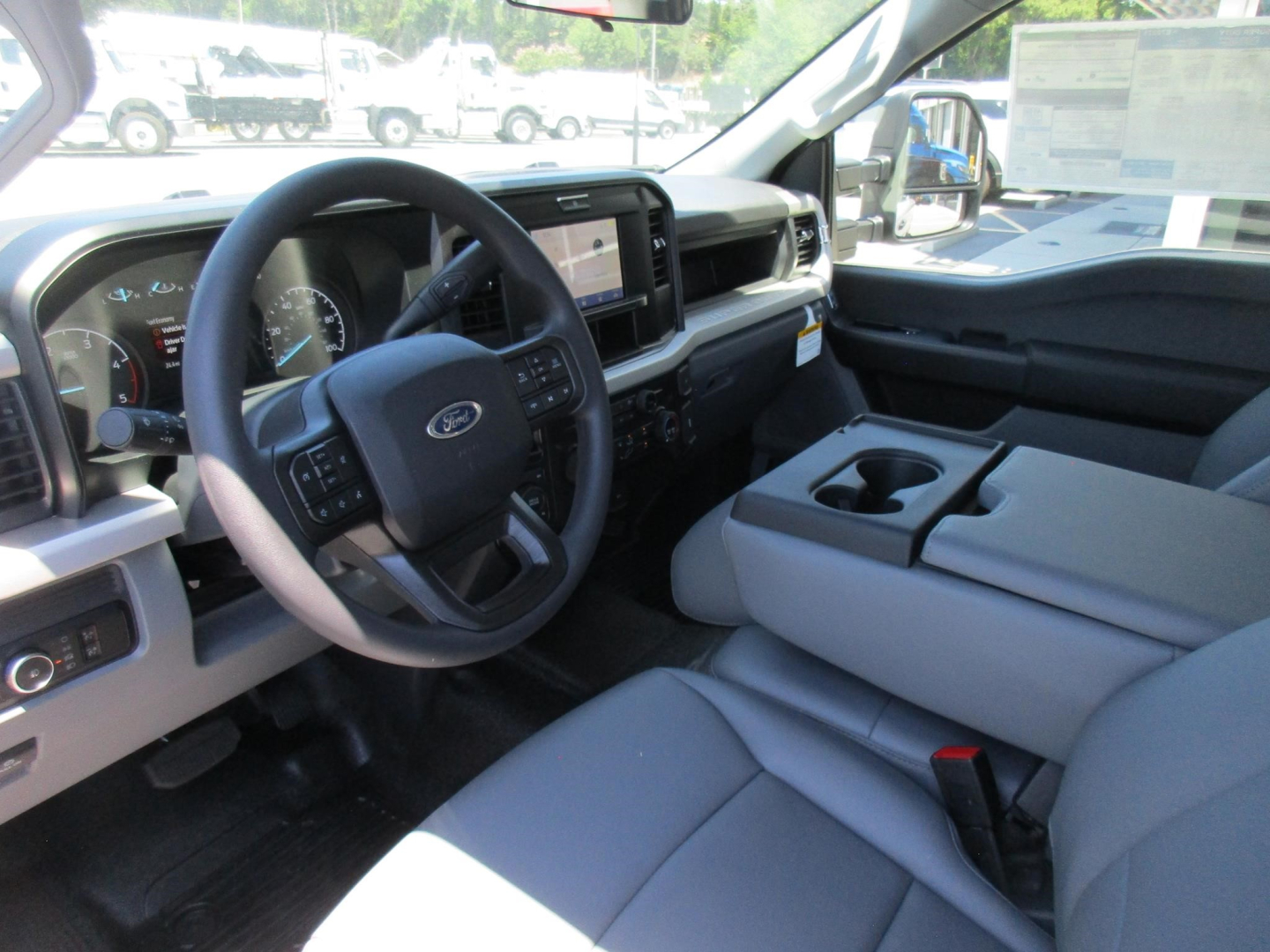 Ford F-250 interior front cabin showing steering wheel with Ford logo, large central touchscreen, dashboard, and front seats from the passenger side.