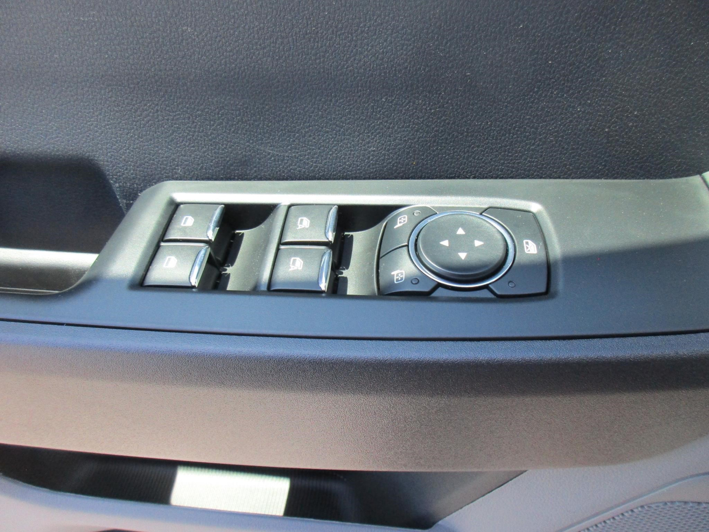 Ford F-250 interior door controls panel with window controls and circular joystick on the driver’s door.