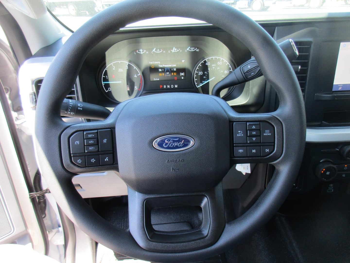 Steering wheel view of a new 2026 Ford F-250 Super Duty dashboard; Ford logo on wheel, instrument cluster visible, control buttons on both sides of the steering column.