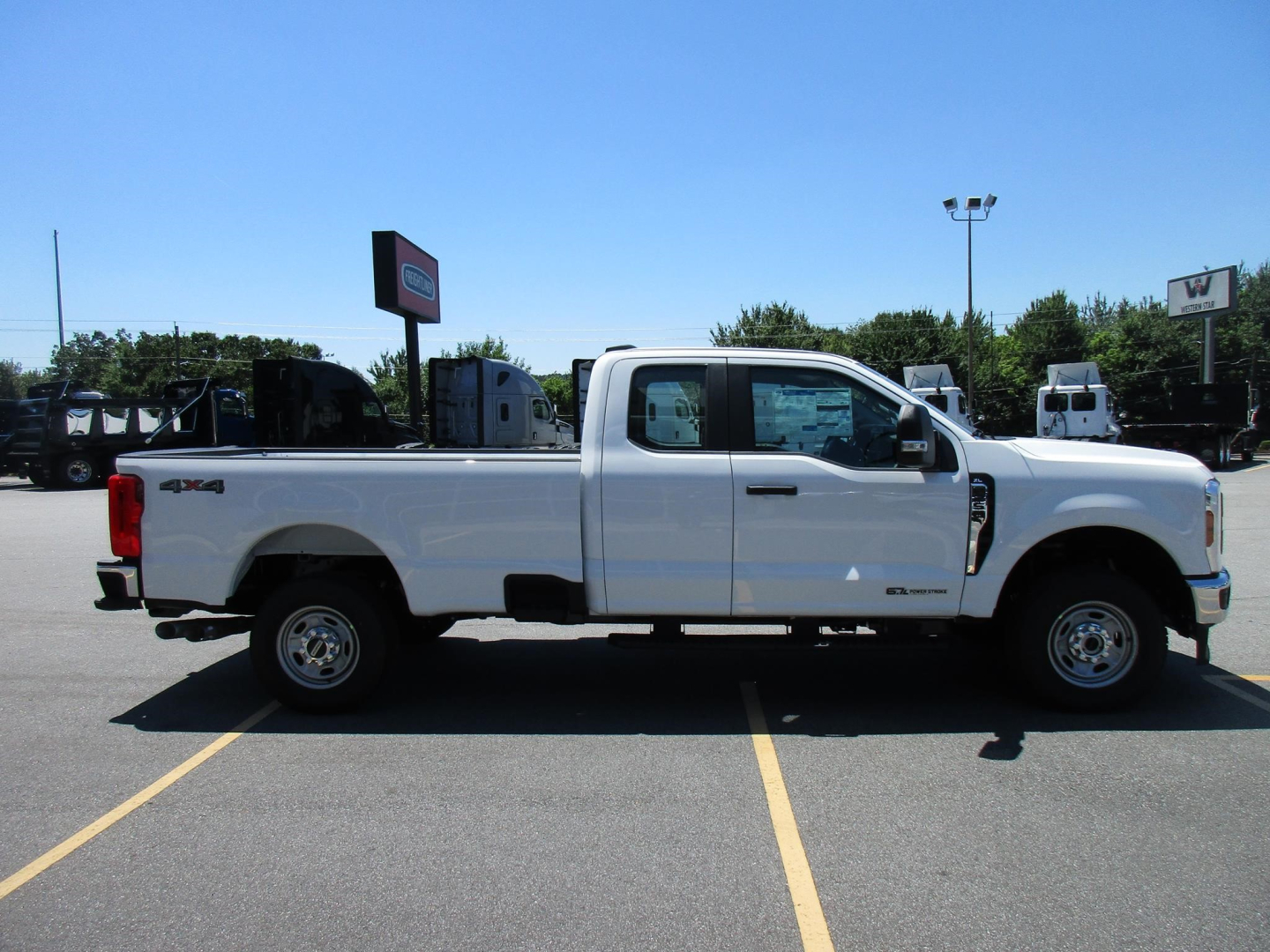Ford F-250 Super Duty pickup truck side view showing extended cab and white paint in a dealership lot.