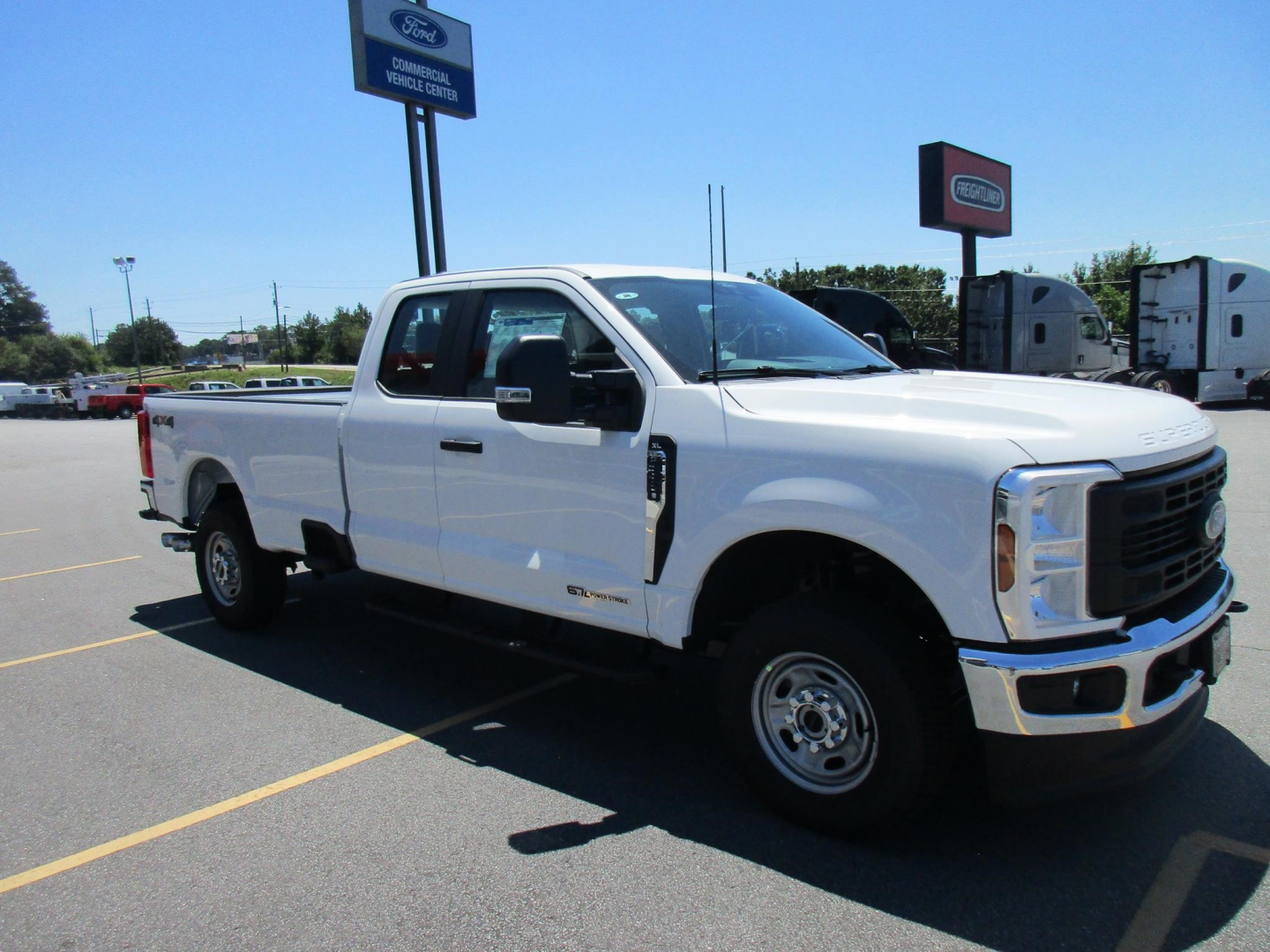 Ford F-250 Super Duty pickup truck, white, crew cab with long bed, side view in dealership lot.