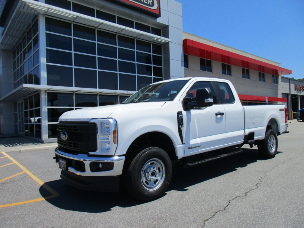 Ford F-250 Super Duty pickup truck in white parked outside dealership showroom.