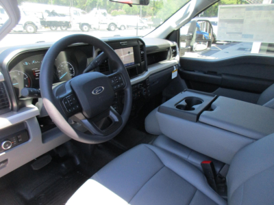 Ford F-250 interior front cabin showing steering wheel with Ford logo, large central touchscreen, dashboard, and front seats from the passenger side.