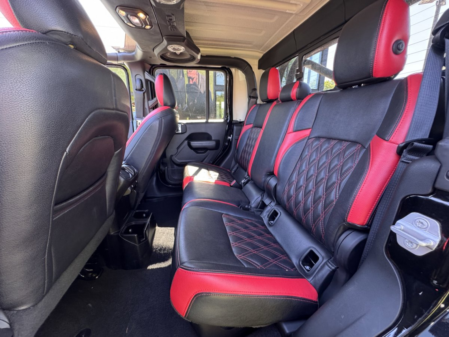 Jeep Gladiator interior showing red and black leather seats in a four-door crew cab with center console and rear seating.