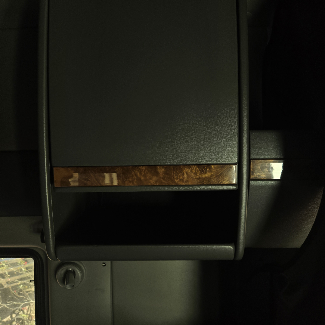Truck interior center console with wood trim accent and storage compartment.