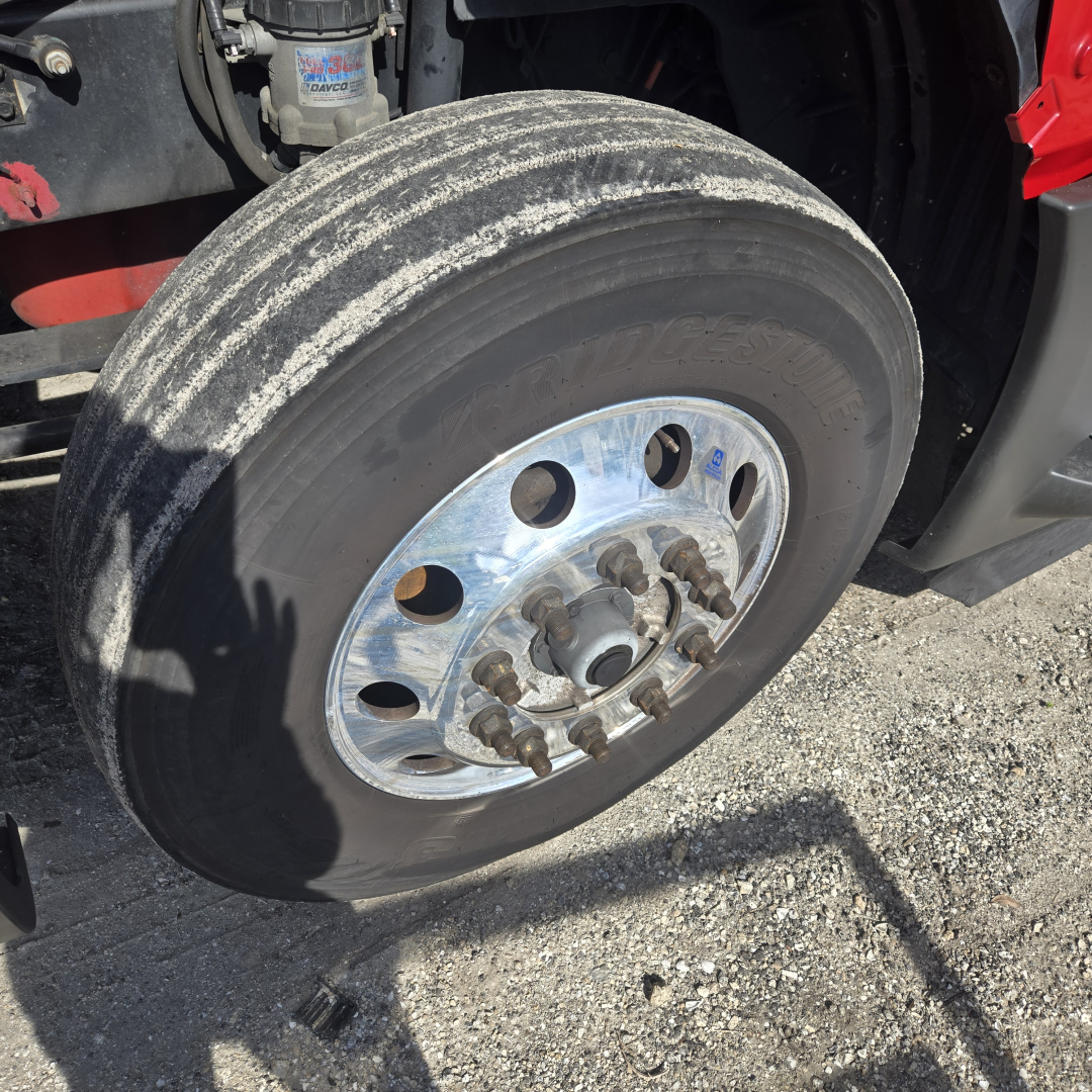 Truck wheel and dual rear axle component visible with polished aluminum rim, lug nuts, and tire tread; part of International LT-series cab over or severe service truck.