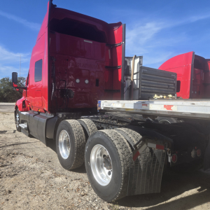 Truck tractor red cab with midroof showing dual rear axles and flatbed trailer attachment.