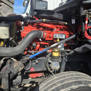 Truck engine bay with a red International LT625 Z-XIS badge, large intake hose, yellow oil filter, and various hoses and wiring visible.
