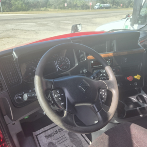 Truck cab interior of a 2020 International LT625 mid-roof showing steering wheel with controls, dashboard gauges, and center console