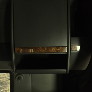 Truck interior center console with wood trim accent and storage compartment.