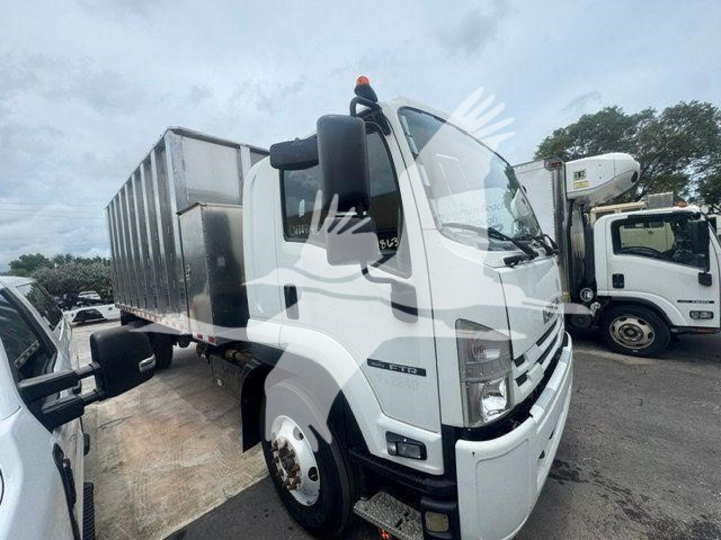 Isuzu flatbed truck cab view showing front grille and side mirror with label area on door