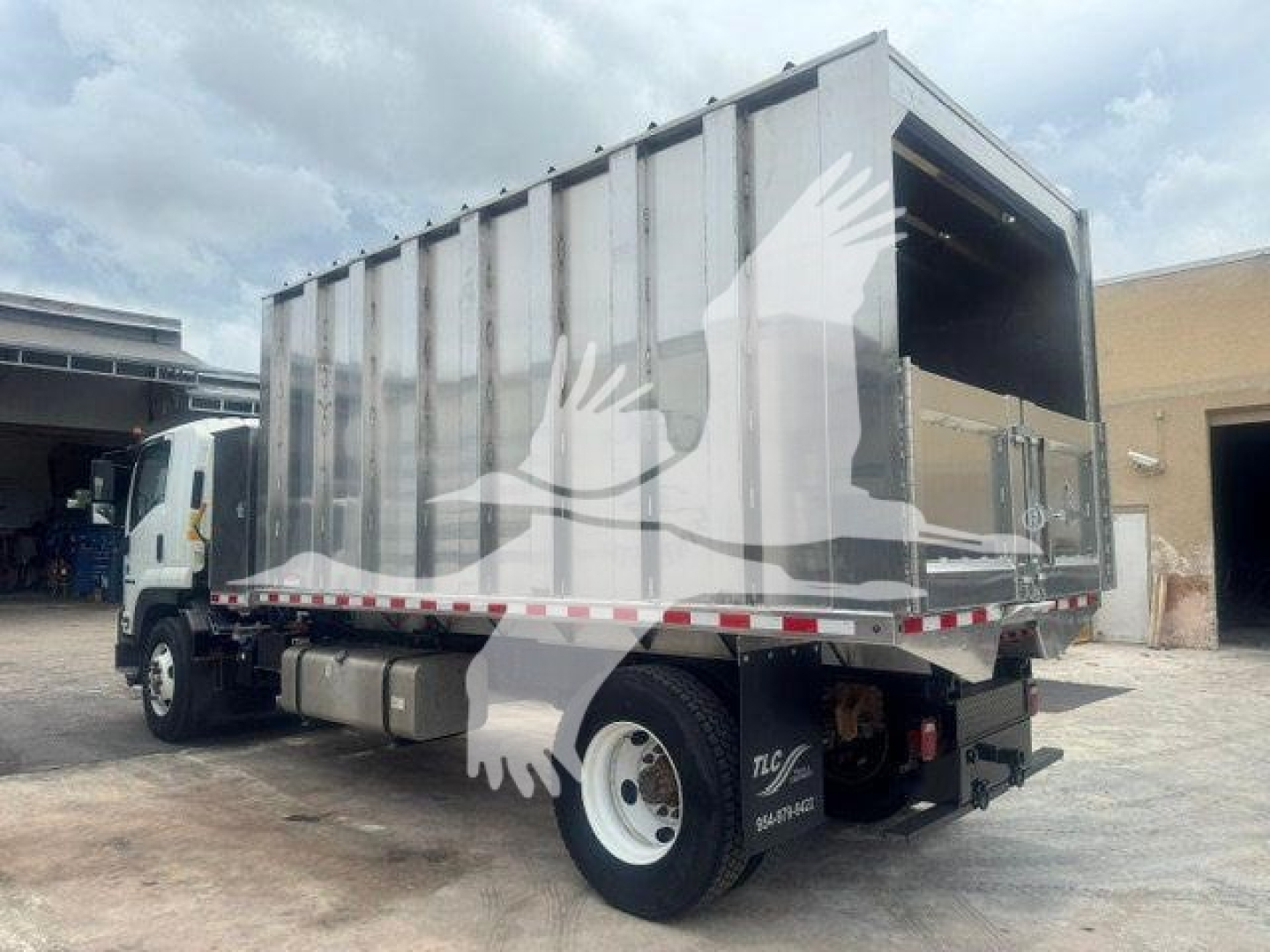 Isuzu FTR dump truck body in service view with cargo bed opened at rear showing large metal cargo area.