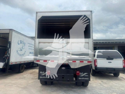 Isuzu NPR or medium-duty truck rear view with raised cargo bed and open top, visible tailgate and bumper