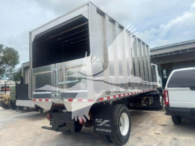 Isuzu NPR/FTA truck cargo bed in a landscape setting with rear dump body open, showing side mirrors and rear bumper; no clear labeled text visible on body except stock/vehicle outlines.