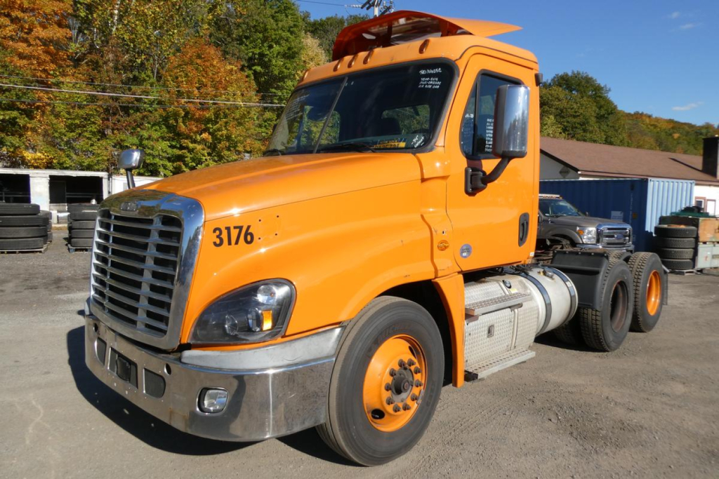 Orange 2016 Freightliner Cascadia 125 daycab truck front-left view showing cab, hood, chrome bumper, and dual rear axles.