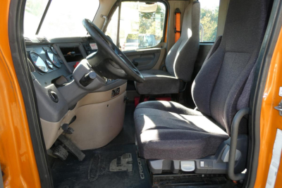 Truck cab interior showing driver seat and dashboard of a Freightliner Cascadia 125 daytime cab.