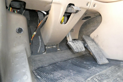 Cab floor area of a 2016 Freightliner Cascadia 125 showing pedals and footwell with wiring harness near accelerator and brake pedals.