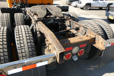 Rear view of a Freightliner Cascadia tractor chassis showing rusty frame, dual rear axles, and taillights with red reflectors.