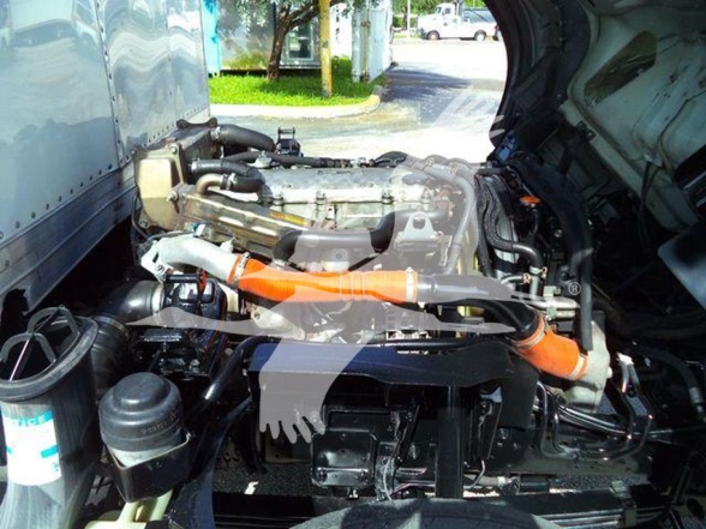 Isuzu NRR truck engine bay with orange hose and exposed components.