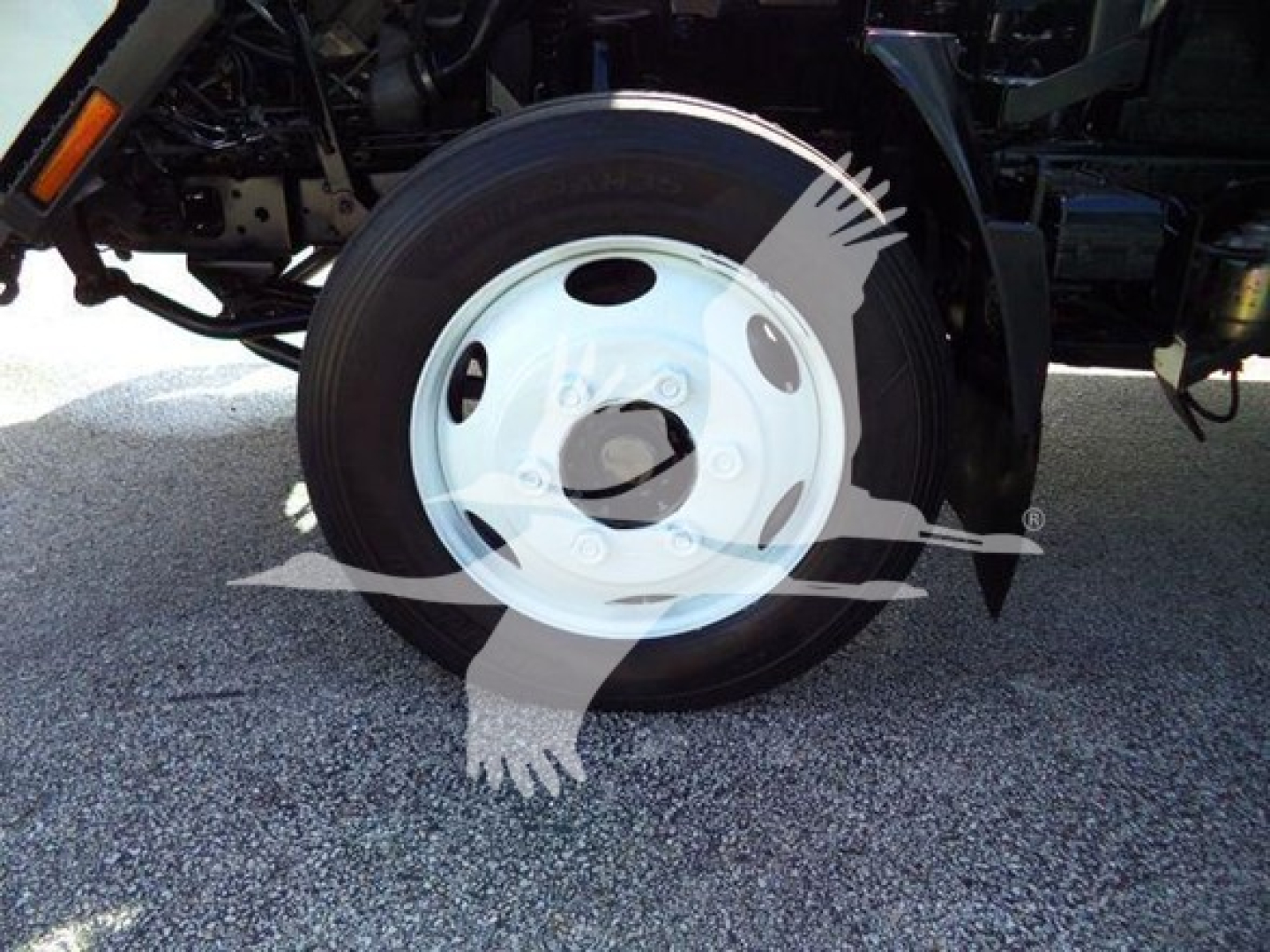 Isuzu NRR front wheel shown with white steel rim and black tire, undercarriage visible.