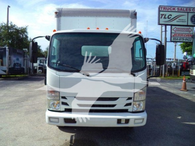 Isuzu NPR/NRR box truck front view showing large windshield, bumper, and side mirrors. Visible sign in background reads TLC Truck Sales. The truck has a white cab with black grille and orange clearance lights.
