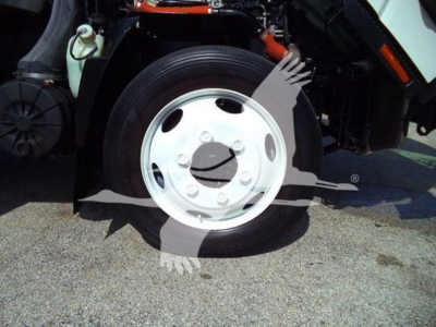 Isuzu NRR front wheel and fender area showing white steel rim and tire, with part of the chassis and hoses visible.