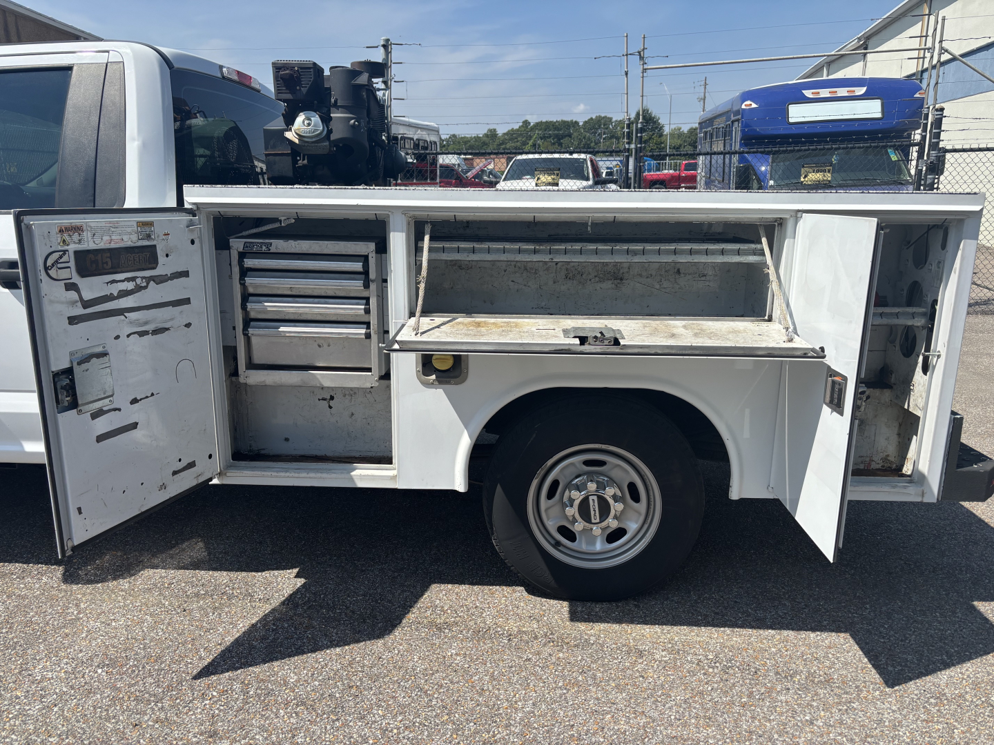 Service body on a Ford F-250 cab and chassis with open tool compartments and storage drawers visible.
