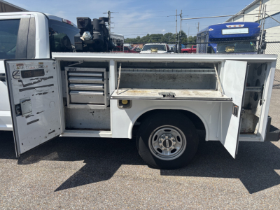 Service body on a Ford F-250 cab and chassis with open tool compartments and storage drawers visible.