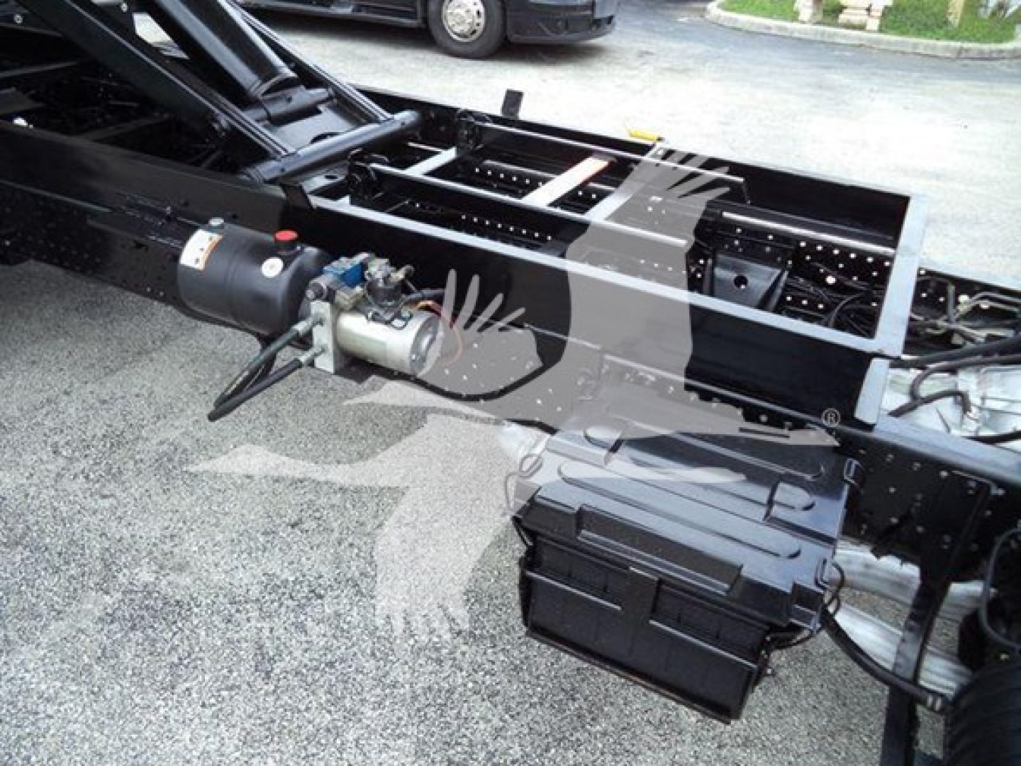 Isuzu NPR HD truck chassis showing mid-frame with hydraulic tank and control box, exposed frame rails, and mounting hardware.