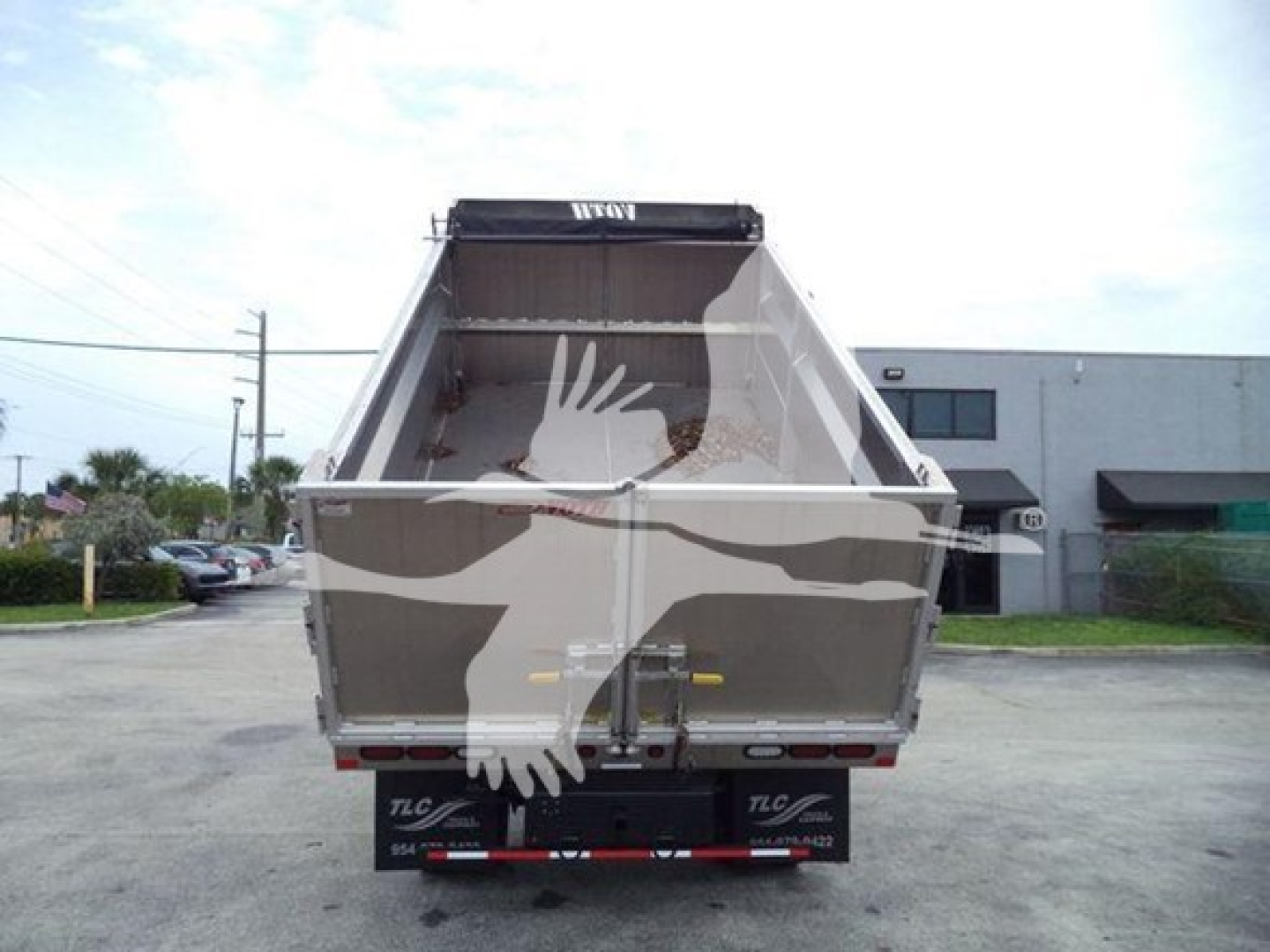 Isuzu NPR-HD dump truck bed showing open cargo area and rear bumper with TLC branding.