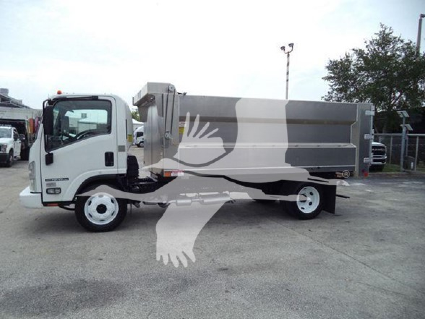 Isuzu NPR-HD truck with a large dump bed, side view showing front cab and gray dumping hopper.