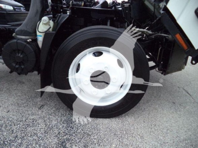 Isuzu NPR HD truck front wheel and suspension components visible; white steel wheel with black tire and surrounding chassis details.