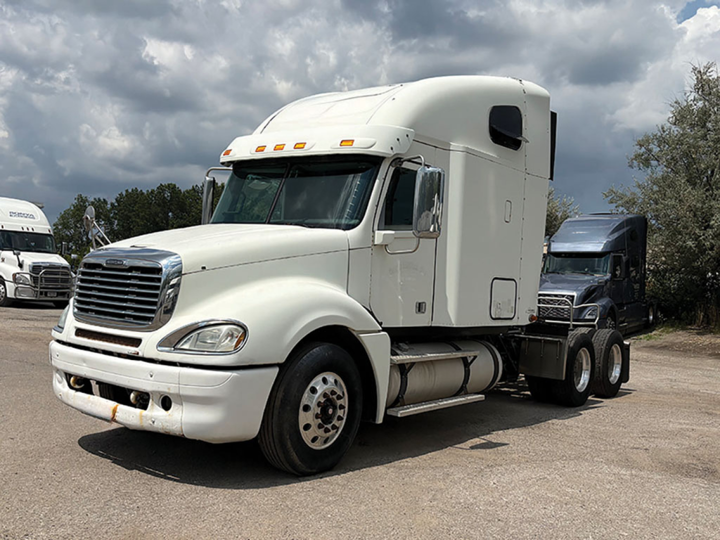 Truck cab in view showing 2014 Freightliner CL120 Columbia, front-left angle, white sleeper cab with chrome grille and dual rear axles.